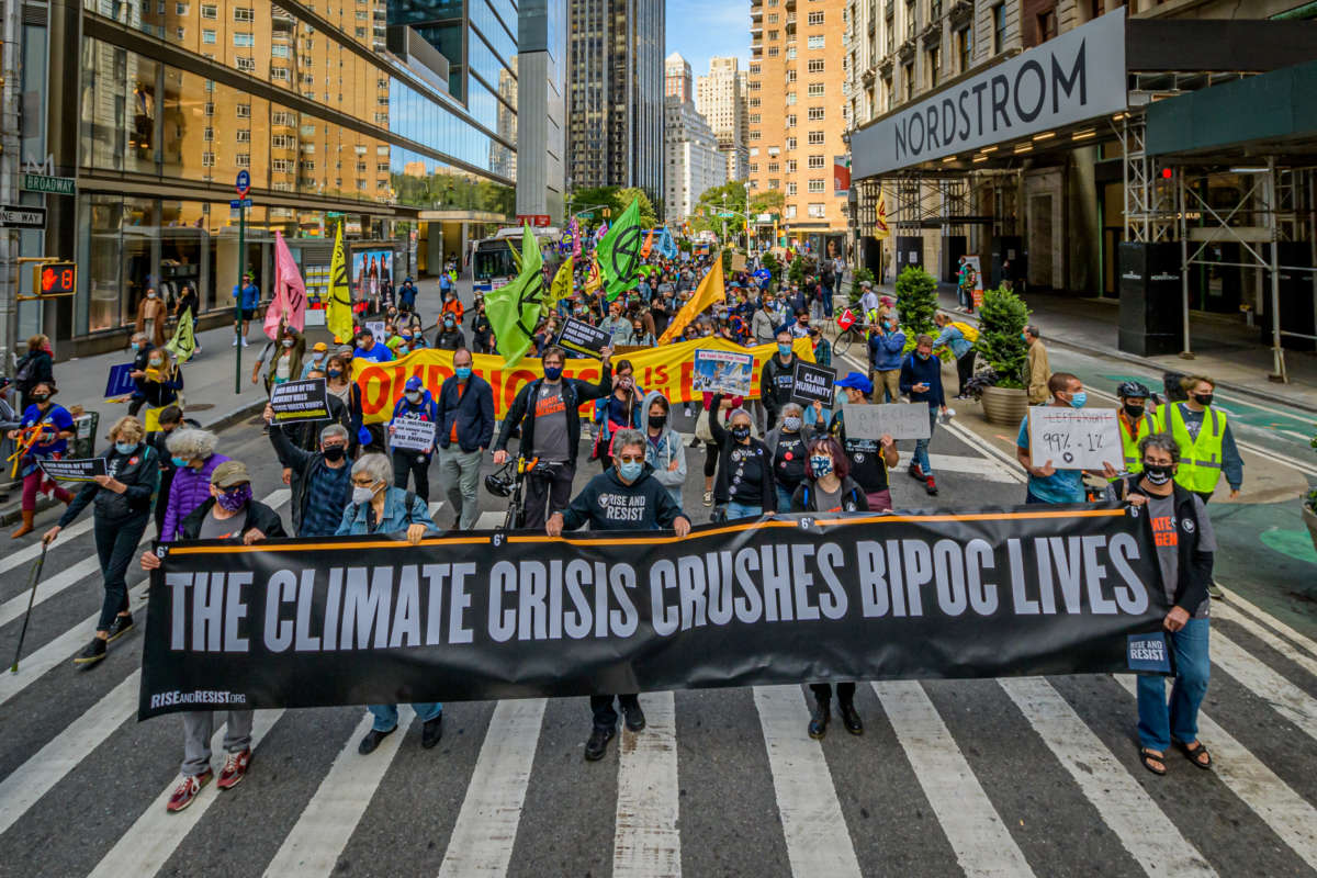 people march behind a banner reading "THE CLIMATE CRISIS CRUSHES BIPOC LIVES" during a protest