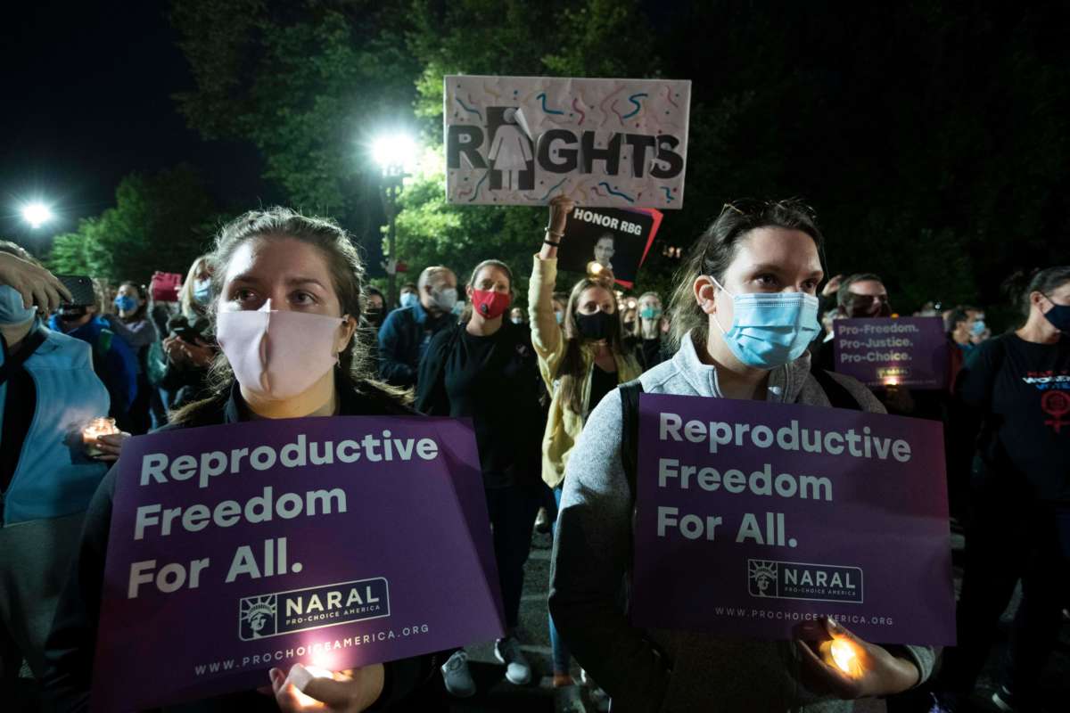 People hold signs supporting reproductive justice at a candlelight vigil