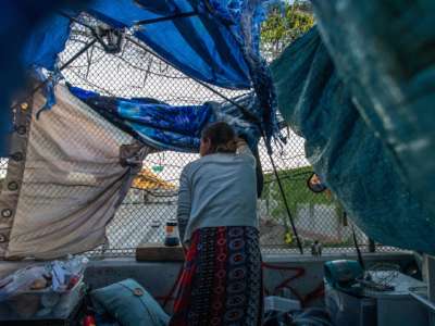 A homeless woman watches cars drive under the overpass she lives on