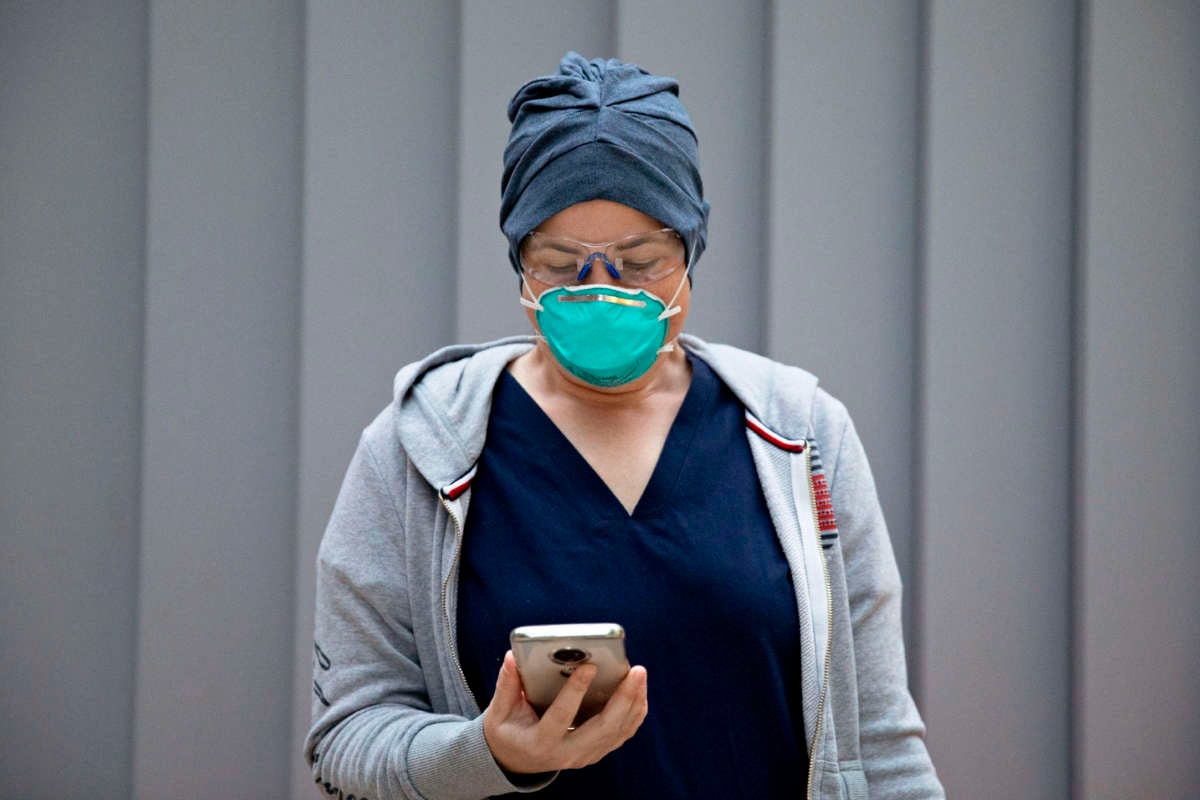 An emergency Department nurse checks her pre-screening app on her phone while wearing personal protective equipment before starting her morning shift at Zuckerberg San Francisco General Hospital and Trauma Center in San Francisco, California, on April 11, 2020.