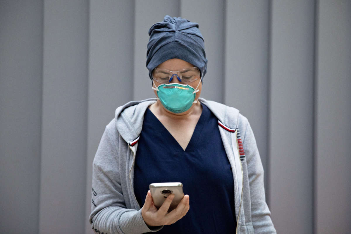 An emergency Department nurse checks her pre-screening app on her phone while wearing personal protective equipment before starting her morning shift at Zuckerberg San Francisco General Hospital and Trauma Center in San Francisco, California, on April 11, 2020.