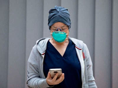 An emergency Department nurse checks her pre-screening app on her phone while wearing personal protective equipment before starting her morning shift at Zuckerberg San Francisco General Hospital and Trauma Center in San Francisco, California, on April 11, 2020.