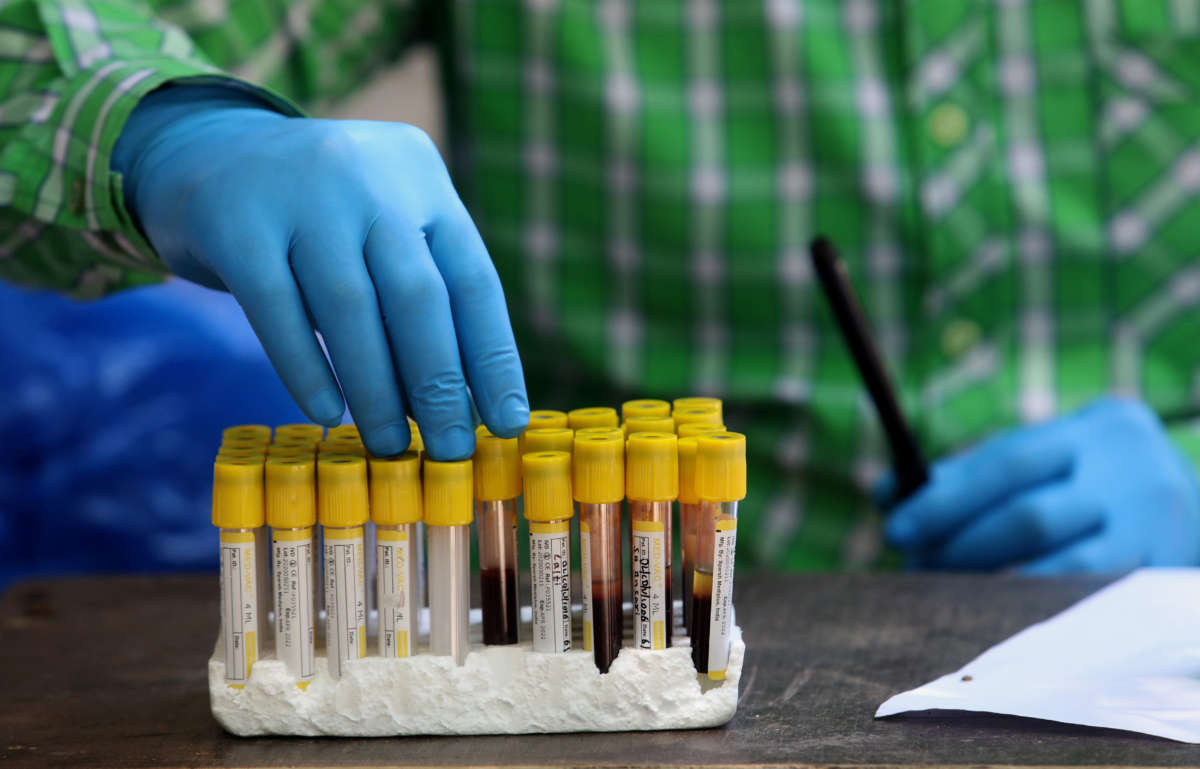 A health worker holds blood samples during a COVID-19 antibody test.