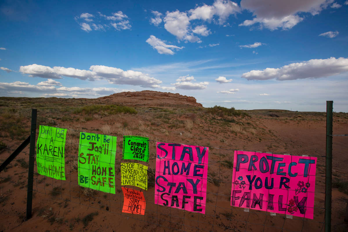 Signs urging people to stay home line a fence