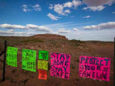 Signs urging people to stay home line a fence