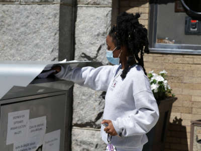 A woman places a ballot in a dropbox outside of Brockton City Hall in Brockton, Massachusetts, on August 26, 2020, before the September 1 Primary Election.
