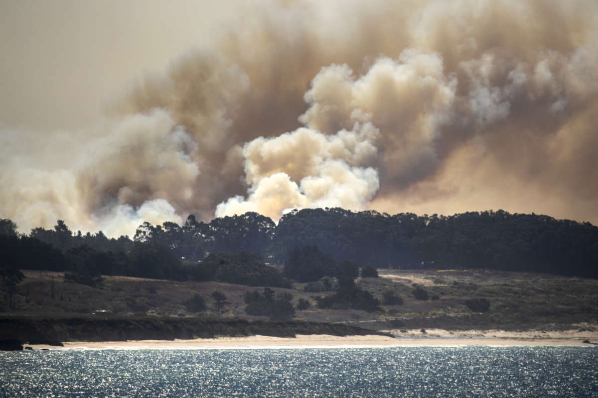 Smoke rises from the CZU Lightning Complex fire burning behind Davenport, California, in a view from Pigeon Point, on August 21, 2020.