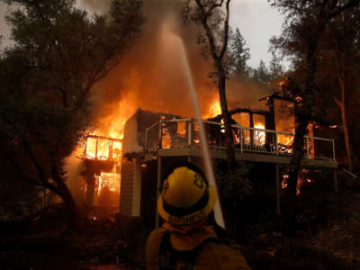 A Cathedral City firefighter puts water on a burning structure at the Meadowood Napa Valley resort in St. Helena, California, on September 28, 2020.