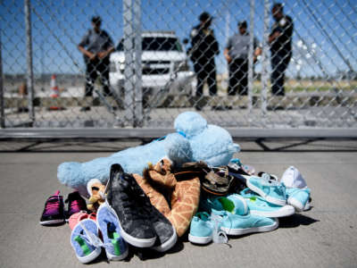 Security personal stand before shoes and toys left at the Tornillo Port of Entry where minors crossing the border without proper papers have been housed after being separated from adults, June 21, 2018, in Tornillo, Texas.