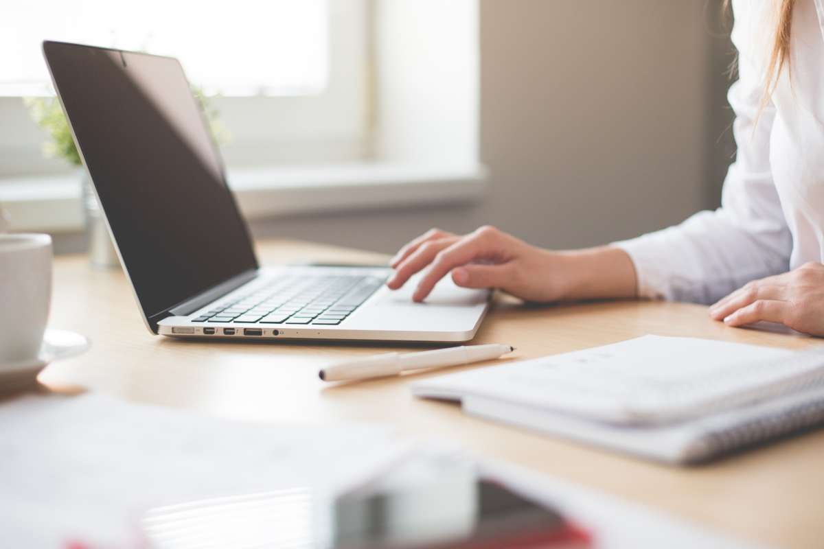 a person at their work from home desk scrolling through their computer.