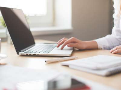 a person at their work from home desk scrolling through their computer.