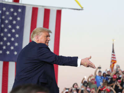 President Trump tosses MAGA face masks into the crowd of cheering supporters as he arrives for a campaign rally at Orlando Sanford International Airport in Sanford, Florida, on October 12, 2020.