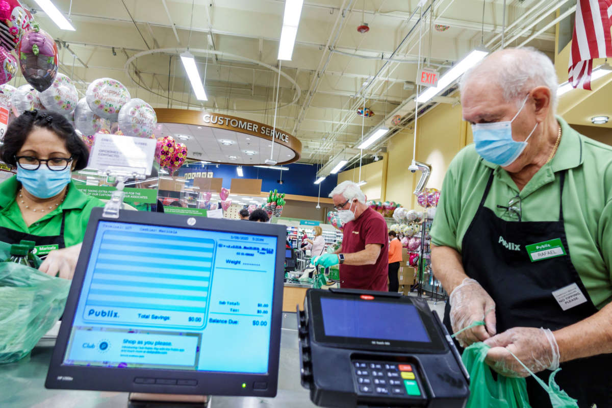 A cashier and bagger wear PPE at a Publix in Miami Beach, Florida, May 8, 2020.