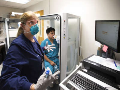 A medical worker helps a patient use hospital equipment