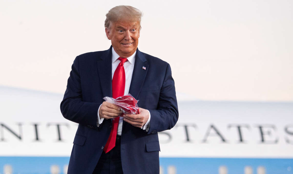 President Trump holds masks before throwing them to supporters as he arrives to hold a rally at Orlando Sanford International Airport in Sanford, Florida, October 12, 2020.