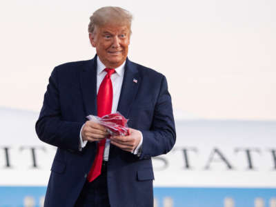 President Trump holds masks before throwing them to supporters as he arrives to hold a rally at Orlando Sanford International Airport in Sanford, Florida, October 12, 2020.