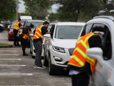 Poll workers receive Vote-by-Mail ballots in a drive thru system setup at the Election Headquarters polling station on October 19, 2020, in Doral, Florida.