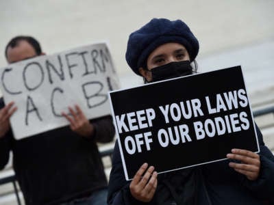 A person displays a sign reading "KEEP YOUR LAWS OFF MY BODY" during a protest on the steps of the us supreme court