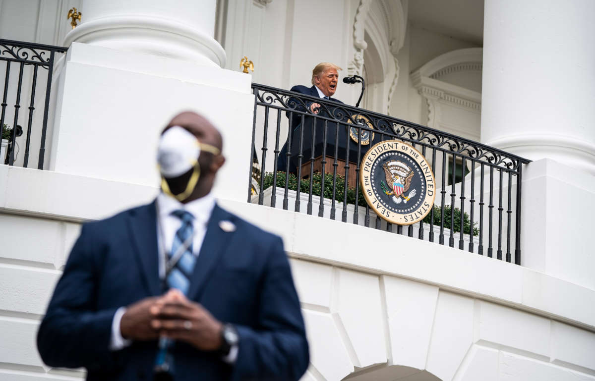 A member of the secret service wearing a face mask stands guard as President Trump speaks to supporters from the Blue Room balcony during an event at the White House on October 10, 2020 in Washington, D.C.