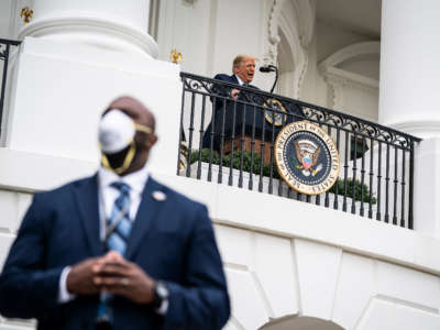 A member of the secret service wearing a face mask stands guard as President Trump speaks to supporters from the Blue Room balcony during an event at the White House on October 10, 2020 in Washington, D.C.