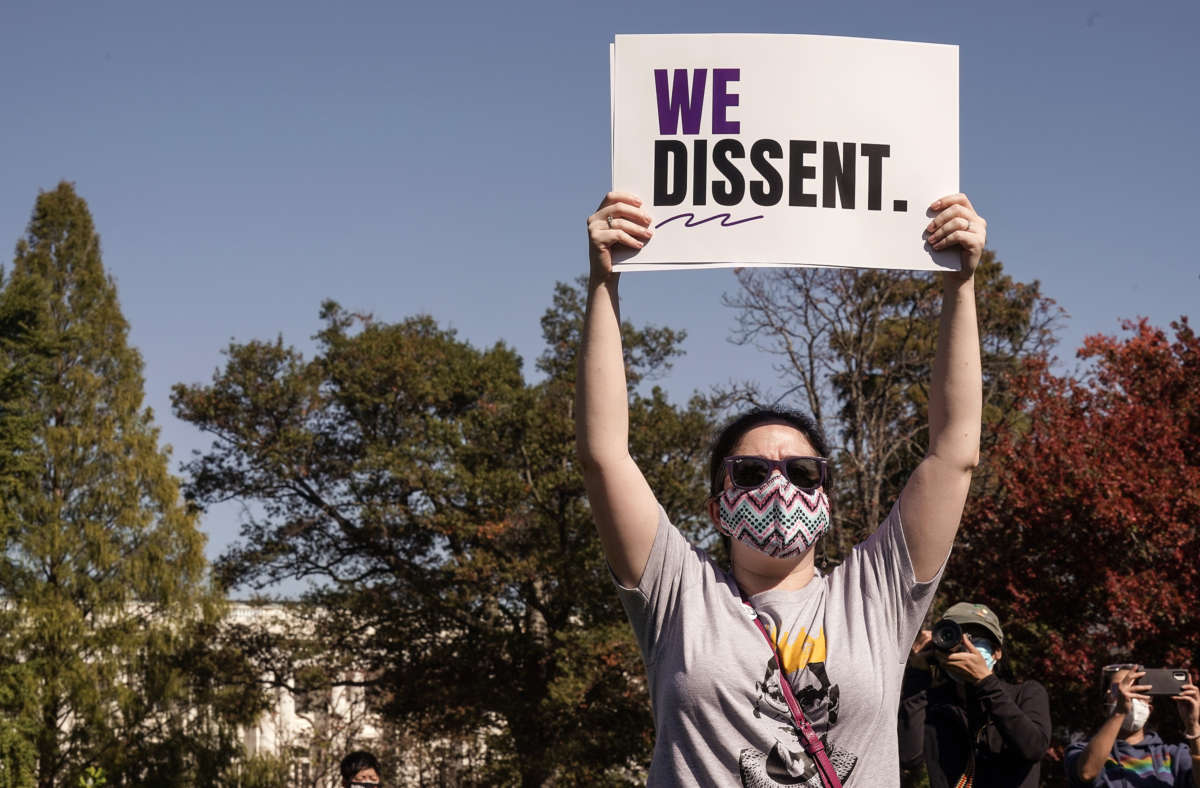 Protester holds a sign reading "WE DISSENT"