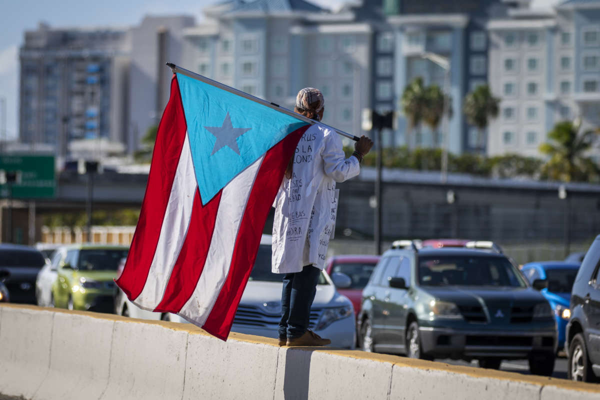 A protester holds a flag during a demonstration calling for the closure of the airport due to the COVID-19 spike in San Juan, Puerto Rico, on August 9, 2020.