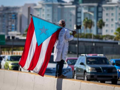 A protester holds a flag during a demonstration calling for the closure of the airport due to the COVID-19 spike in San Juan, Puerto Rico, on August 9, 2020.