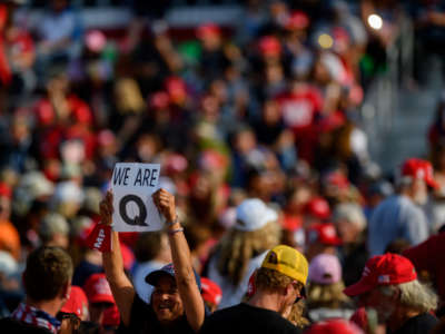 A woman holds up a QAnon sign to the media as attendees wait for President Donald Trump to speak at a campaign rally at Atlantic Aviation on September 22, 2020, in Moon Township, Pennsylvania.