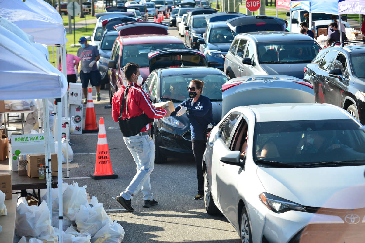 Volunteers help load food as vehicles arrive to pick up food supplies and essential items during a Feeding South Florida Drive-Thru Food Distribution at Miramar Regional Park on November 19, 2020, in Miramar, Florida.