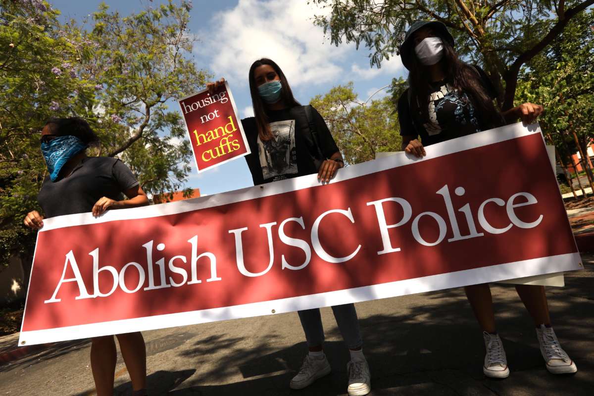 Masked students hold a banner reading "ABOLISH USC POLICE" during a protest