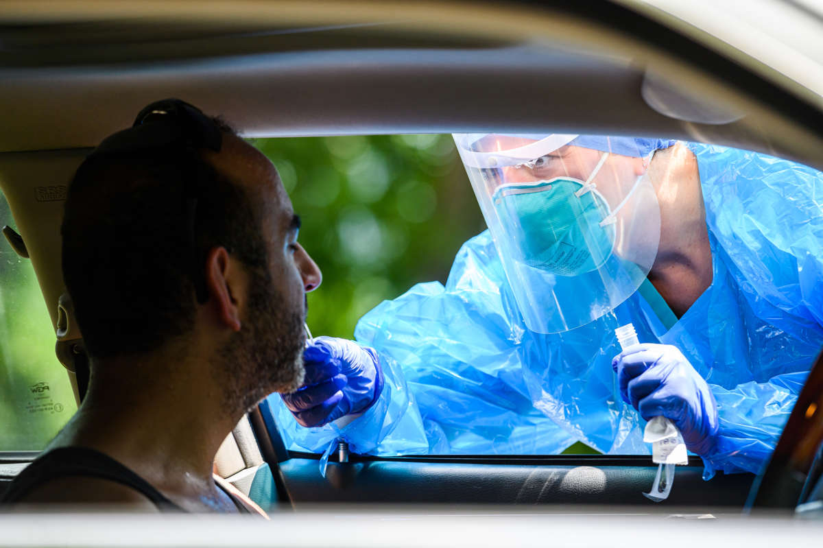 A medical professional administers a covid test to a patient through a car window