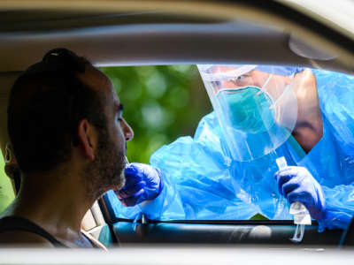 A medical professional administers a covid test to a patient through a car window