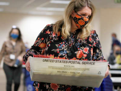 An election worker carries mail-in ballots in containers from the U.S. Postal Service to be processed by election workers at the Salt Lake County election office in Salt Lake City, Utah, on October 29, 2020.