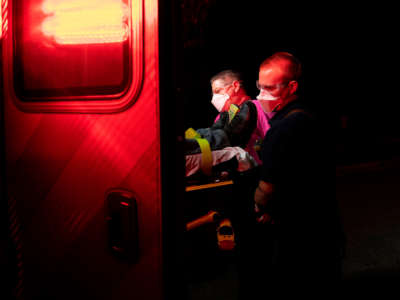 Firefighters and paramedics with Anne Arundel County Fire Department wear enhanced Personal Protective Equipment as they load a patient into an ambulance on October 26, 2020, in Glen Burnie, Maryland.