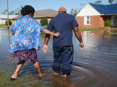 Patrick King and Soncia King walk through flood waters from Hurricane Delta toward their home, which they were still repairing from damage from Hurricane Laura, on October 10, 2020, in Lake Charles, Louisiana.