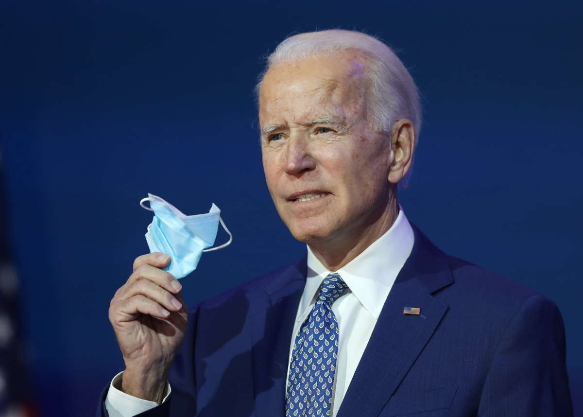 President-elect Joe Biden holds a protective mask as he speaks to the media after receiving a briefing from the transition COVID-19 advisory board on November 9, 2020, at the Queen Theater in Wilmington, Delaware.