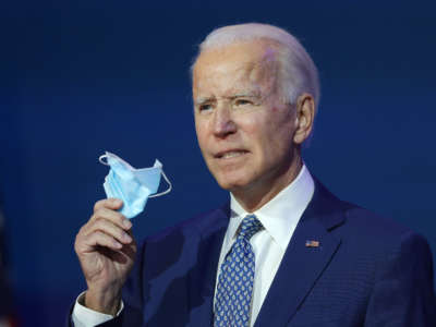 President-elect Joe Biden holds a protective mask as he speaks to the media after receiving a briefing from the transition COVID-19 advisory board on November 9, 2020, at the Queen Theater in Wilmington, Delaware.