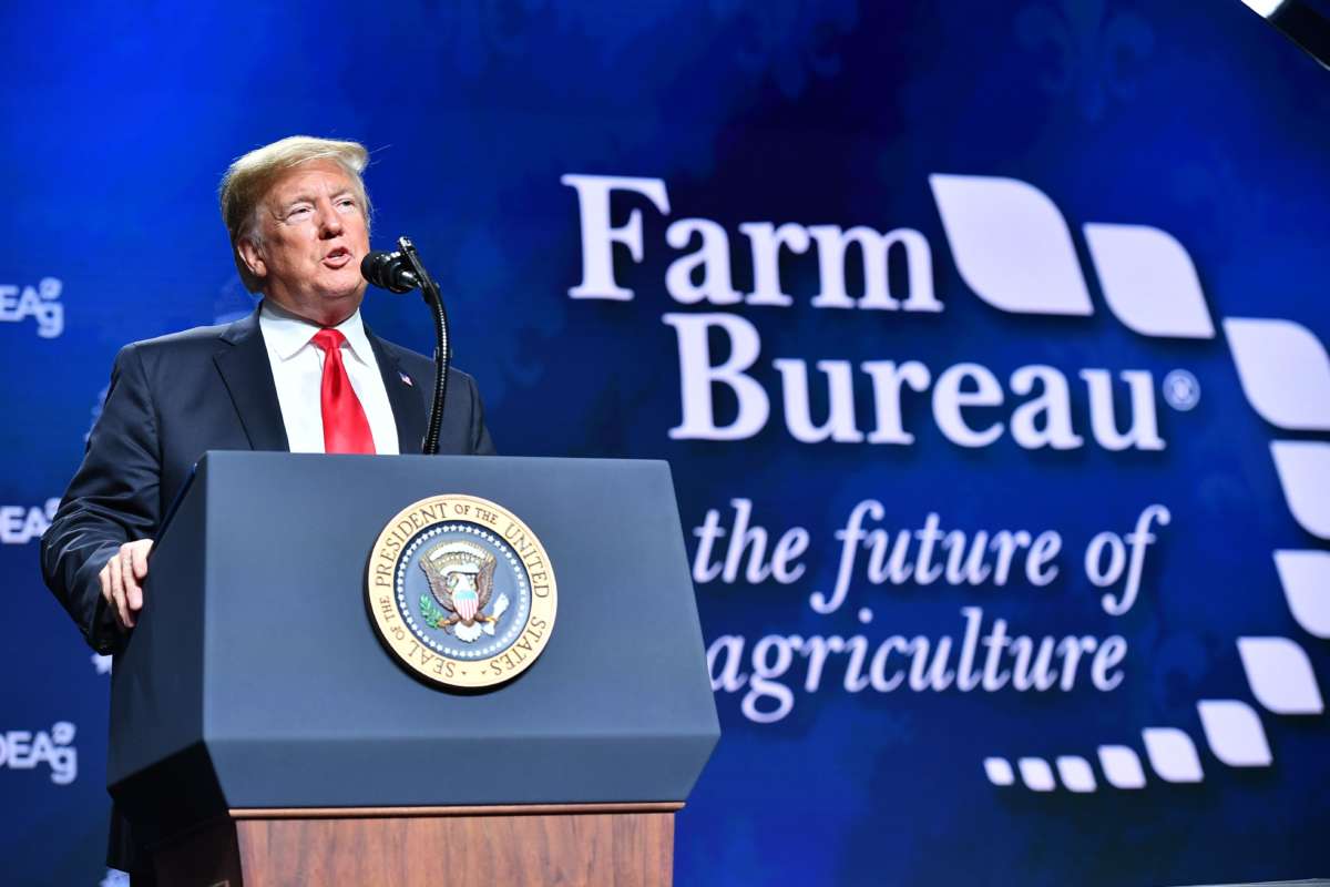 Donald Trump speaks in front of a blue backdrop reading "Farm Bureau"