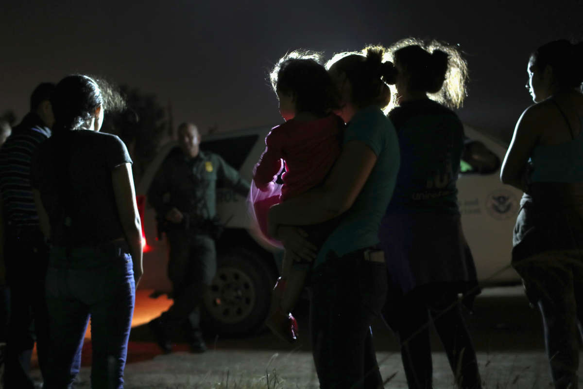 A Honduran mother holds her two-year-old as U.S. Border Patrol agents take them and other migrants into custody at the U.S.-Mexico border on June 12, 2018, in McAllen, Texas.