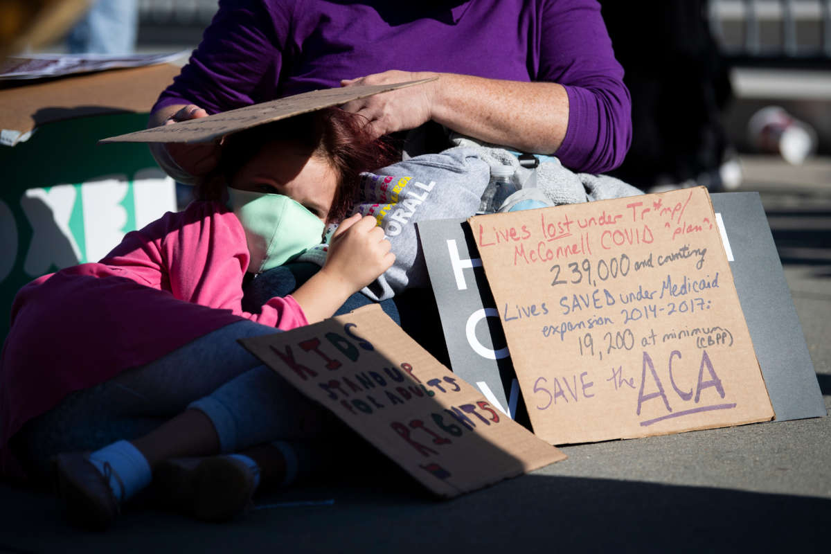 A girl lays on a woman's lap outside the Supreme Court as it hears oral arguments that challenge the Affordable Care Act on November 10, 2020, in Washington, D.C.