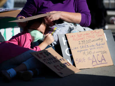 A girl lays on a woman's lap outside the Supreme Court as it hears oral arguments that challenge the Affordable Care Act on November 10, 2020, in Washington, D.C.