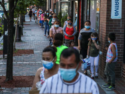 Hundreds of community members line up early to pick up food boxes at Chelsea Collaborative during their weekly food drive in Chelsea, Massachusetts, on July 15, 2020.