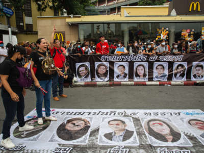 Protesters stamp their feet on posters with Junta government leaders and the government-sided politicians during a demonstration in Bangkok, Thailand.