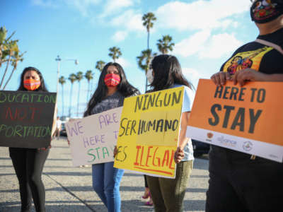 People hold signs during a rally in support of the Supreme Court's ruling in favor of the Deferred Action for Childhood Arrivals program, in San Diego, California, June 18, 2020.