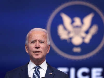 Joe Biden stands in front of a blue backdrop