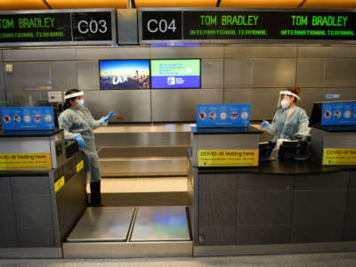 Staff members wear personal protective equipment at an airport COVID-19 testing location inside the Tom Bradley International Terminal at Los Angeles International Airport in Los Angeles, California, on November 18, 2020.