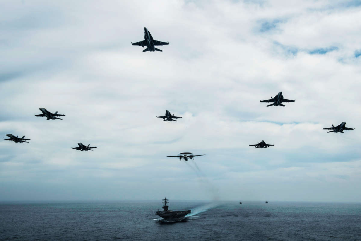 Aircraft fly in formation over the USS Nimitz in the Pacific Ocean, June 2, 2020, while the aircraft carrier is underway for a composite training unit exercise.