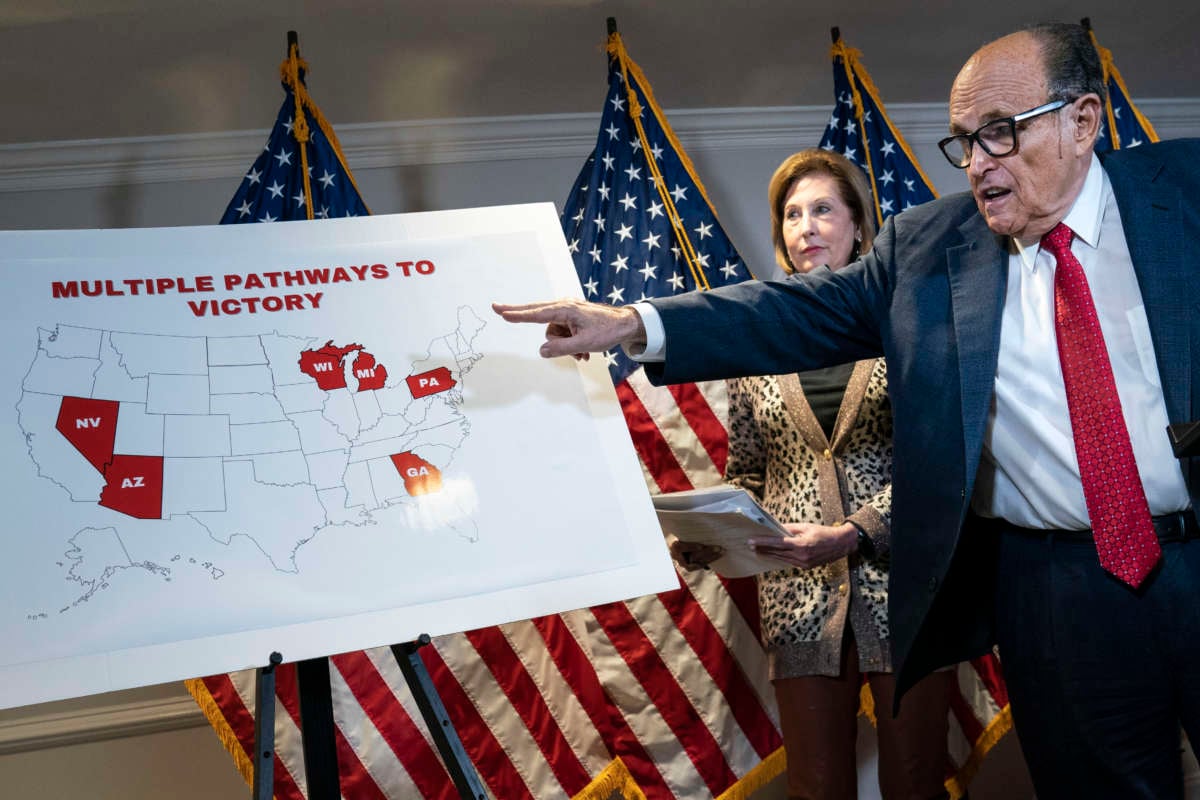 Rudy Giuliani points at a map as hairdye-stained sweat drips down his face