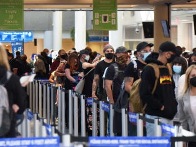 People wait in line at a TSA security checkpoint at Orlando International Airport on Thanksgiving eve, November 25, 2020, in Orlando, Florida.