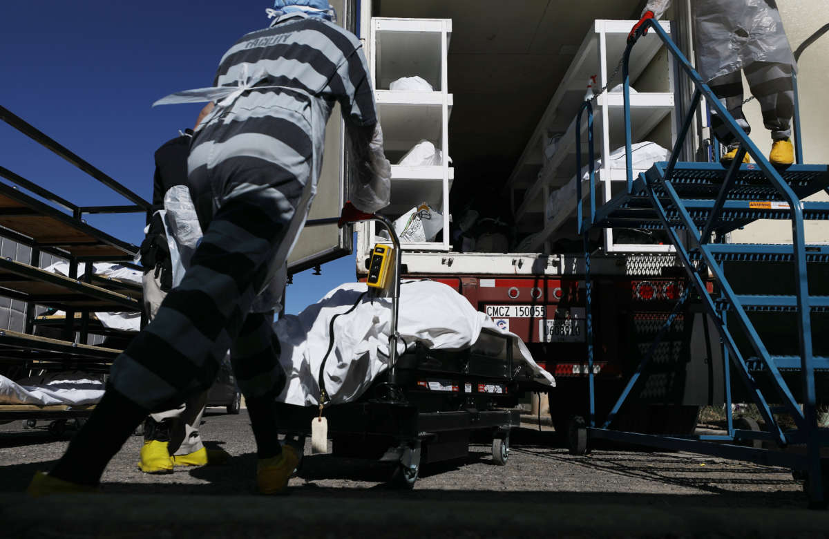 Inmates from El Paso County detention facility load bodies wrapped in plastic into a refrigerated temporary morgue trailer in a parking lot of the El Paso County Medical Examiner's office on November 16, 2020, in El Paso, Texas.